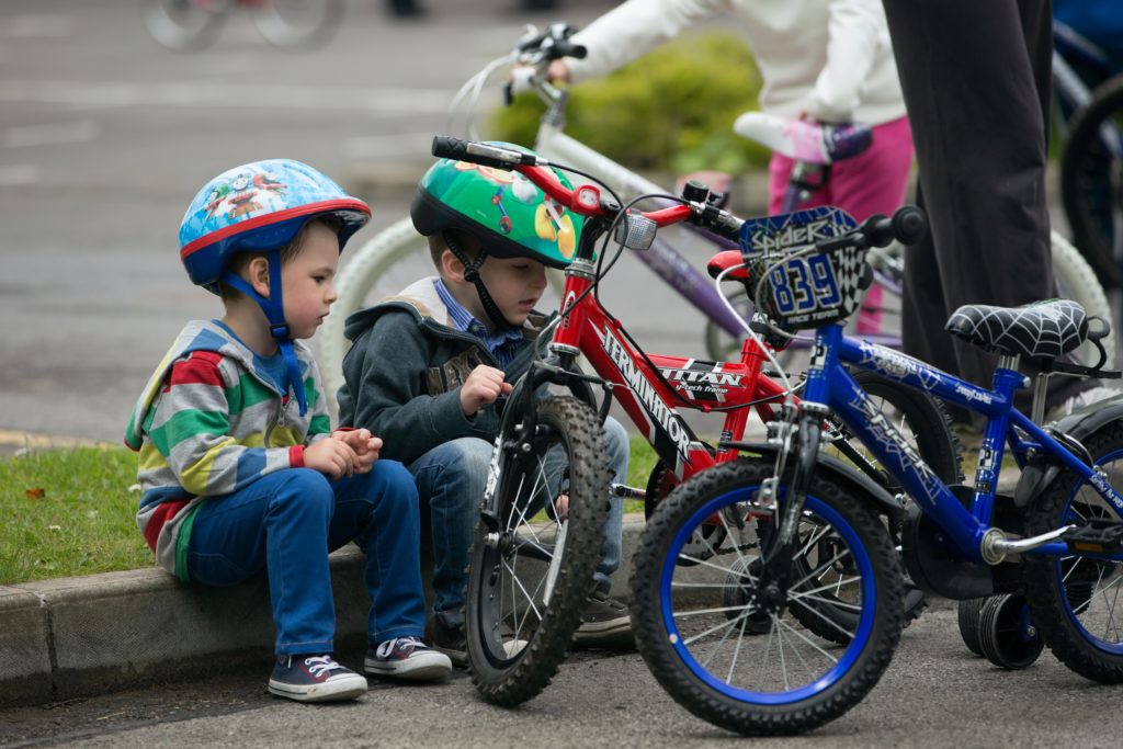 Kinder betrachten ihre Räder und beugen so Verletzungs- und Sicherheitsrisiken vor.  